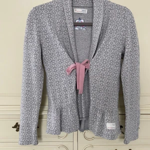 Odd Molly tröja  - Grå stickad tröja med rosa band från Odd Molly i strlk 2/M. Tröjan är i fint skick. Varit ett pyttelitet hål på ena armen som är lagat så det syns inte. Nypris 1500 kr