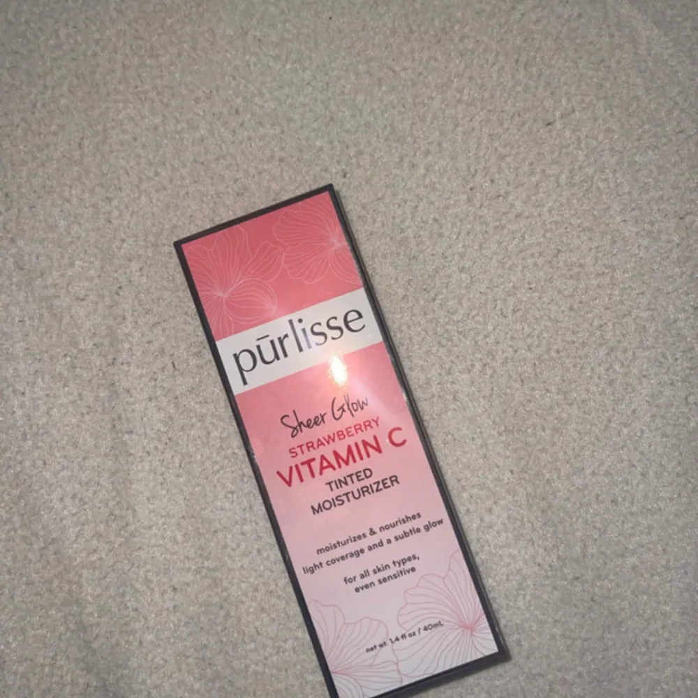 Säljer en Purlisse Sheer Glow Strawberry Vitamin C Tinted Moisturizer. Denna fuktkräm ger en lätt täckning och en subtil lyster, perfekt för alla hudtyper. Innehåller vitamin C och jordgubbsextrakt för att ge huden en fräsch och strålande look. Tuben är i en söt rosa färg och innehåller 40 ml produkt.. Skönhet.