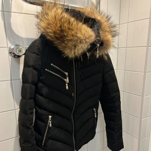 Hollies vinterjacka  - Figursydd snygg vinterjacka! Stor luva och skönt att kunna dra dragkedjan högt upp. Inga skador 