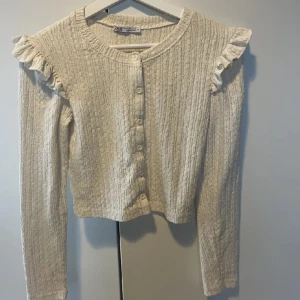 Säljer en jättefin trendig kofta som aldrig är använd i helt nyskick  - Koftan är i nyskick och har knappar och volanger