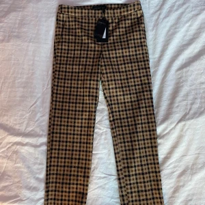 Byxor  - Brun/beige rutiga oanvända byxor från märket STOCKHLM. Midwaisted och ganska raka, men blir lite smalare vid smalbenen. Väldigt bekvämt material.