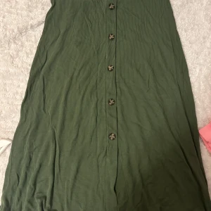 Utsvängd grön kjol  - Säljer denna söta gröna kjolen då jag har så mycket annat jag använder mer av, strl M men passar S också, ribbad med knappar, resårband som drar in midjan fint💚