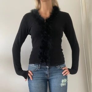Svart fjäder tröja - En super fin tröja med fjädrar längst kragen och ned. Perfekt till hösten!!!