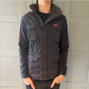 Field jacket  - Säljer asfet field jacket från superdry ganska sällsynt aldrig sett någon med en likadan. Storlek m sitter perfekt på dig som är 180-185 perfekt jacka för  vintern som kommer . Den är svart/ mörk blå. Byten är intressanta