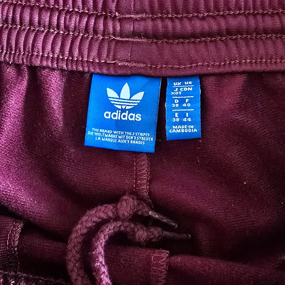 Ännu ett par Adidas Track Pants-byxor i min samling som förtjänar att nyttjas vidare och oftare!  Dessa supercoola i burgundy-färg är sjukt snygga att matcha mellan olika stilar.  Färg: Burgundy/vinröd/lilaröda  Midja: 38 cm (medium) med stretch och . Jeans & Byxor.