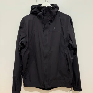 Svart vindjacka från Peak Performance - Säljer en svart vindjacka från Peak Performance. Den är 100% vind- och vattentät. Jackan har en justerbar huva. Perfekt för höstens blåsiga och regniga dagar!