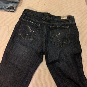Lågmidjade Tommy Hilfiger jeans - Mörka lågmidjade Tommy Hilfiger jeans som är försmå för mig i midjan vilket syns. Står storlek 27/34 men det stämmer ej. Storlek Xs i midjan och längd 34. Perfekta på mig som är 172cm. Använda men bra skick