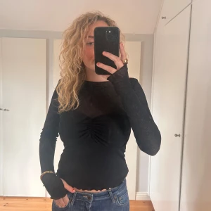 Svart långärmad topp från Gina Tricot - Säljer en snygg svart långärmad topp från Gina Tricot. Den har en tight passform och en fin rynkdetalj framtill. Perfekt för både vardag och fest!🍂💃🖤