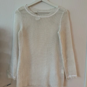 Vit nättröja - Säljer en cool vit nättröja med långärmad design. Perfekt för lager-på-lager-stil eller som ett statement-plagg. Tröjan är i ett syntetmaterial som ger en luftig och lätt känsla. Passar perfekt för vår och sommar!