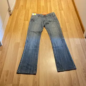 (16) Ljusblåa lågmidjade bootcut jeans helt nya med lappar kvar, med brodering på fickorna. Midjemått rakt över: 36cm, innerbenslängd 84 cm 🩵