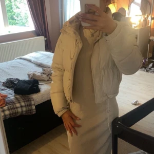 Beige pufferjacka - Säljer en supermysig beige pufferjacka som är perfekt för kyliga dagar. Jackan har en dragkedja framtill och är långärmad. Den är croppad och har en snygg, modern stil. Perfekt för både höst och vinter!