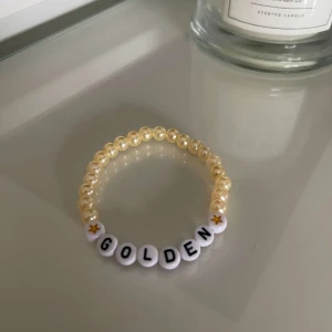 Guldigt pärlarmband med text - Säljer ett supergulligt armband med guldiga pärlor och bokstavspärlor som bildar ordet 'GOLDEN'. Perfekt för att ge en personlig touch till din outfit. Armbandet är elastiskt och passar de flesta handleder. ✨