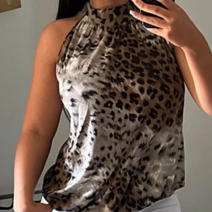 Leopardmönstrad halterneck-top - Säljer en supercool leopardmönstrad halterneck-top. Den är ärmlös och har en snygg knytning i nacken som ger en öppen rygg. Perfekt för en utekväll eller fest! Materialet känns mjukt och bekvämt.