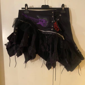 Svart kjol med snörning och dragkedja L - Helt ny kjol med lila broderad elgitarr på. Storlek L.