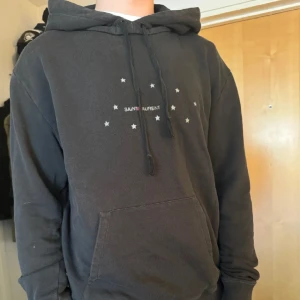 Saint Laurent Hoodie -  Fet svart YSL I storlek small (Passar M), modellen är 176 cm, 66kg🙌 Köpt på StoreEnda så självklart äkta! Pris: 1699kr Tröjan har en liten defekt vid ärmen men inget som är så stort.