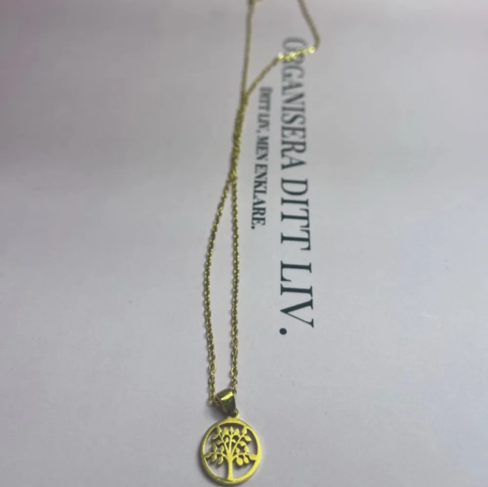 Elegant guldhalsband med ett hänge i form av livets träd. Kedjan är tunn och smidig, vilket ger en stilren look. Perfekt för att lägga till en touch av symbolik och elegans till din outfit. Aldrig använd. Säljer för 70 kronor.✨. Asusteet.