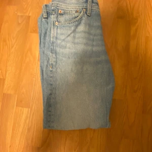 Ljusblå jeans från Jack & Jones - Snygga ljusblå jeans från Jack & Jones med klassisk femficksdesign. De har en knappgylf och bälteshällor, perfekt för en avslappnad stil. Märkeslappen i läder baktill ger en extra touch.