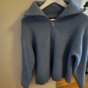 Blå ribbad tröja från Bikbok - Säljer en snygg blå ribbad tröja från Bikbok med dragkedja och hög krage. Perfekt för kyliga dagar med sin mysiga och stilrena design. Tröjan har långa ärmar och en avslappnad passform.