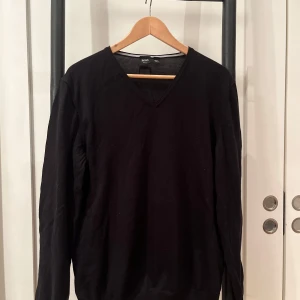 Svart tröja från Boss - Snygg svart tröja från Boss med v-ringad hals. Perfekt för en stilren look. 