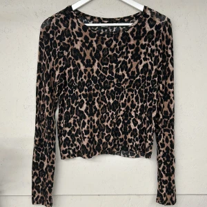 Leopardmönstrad topp från Gina Tricot - Säljer en snygg leopardmönstrad topp från Gina Tricot. Toppen är långärmad och croppad, perfekt för att ge en trendig look. Den har en bekväm passform och är tillverkad i ett mjukt material.