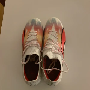 fotbollsskor från Puma - Snygga fotbollsskor från Puma i en mix av vitt, orange och blått med svarta detaljer.