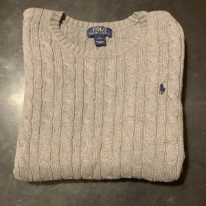 Grå stickad tröja från Ralph Lauren - Säljer en stilren grå stickad tröja från Ralph Lauren. Den är i bra form, storleken är L i 14 - 16 åringar men funkar som en XS eller S vuxen form pris är diskuterbart, funka för båda könen.
