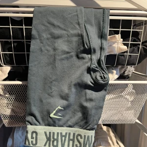 Gröna leggings från Gymshark - Snygga gröna leggings från Gymshark med hög midja och elastisk linning. Perfekta för träning med en bekväm passform och stilren design. Logotypen syns tydligt på linningen.