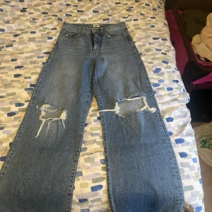 Blå jeans med slitningar - Snygga hög midjade blå jeans med slitningar på knäna från lager 157. De är lite slitna nere i fötterna. Säljer då jag rensar garderoben och använder de inte.💕