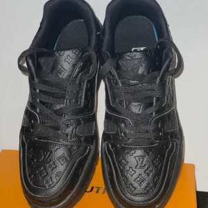 Svarta sneakers med monogramdetaljer - Snygga svarta sneakers med präglade monogramdetaljer. Skorna har snörning och en stilren design som passar perfekt för en trendig look. Tillverkade i skinn för en lyxig känsla.