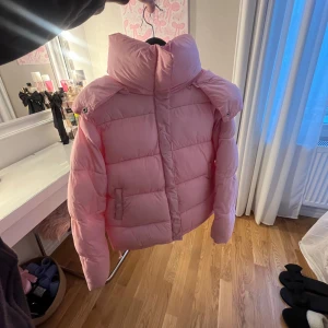 Bikbok dunjacka - Säljer en fluffig rosa dunjacka med hög krage och avtagbar huva. Jackan har långa ärmar och stängs med dragkedja. Perfekt för kyliga dagar när du vill hålla dig varm. Bikbok har slutat sälja denna jacka. Har 2 andra i samma modell, i andra färger. Därav behöver jag göra av mig med 1. 💕