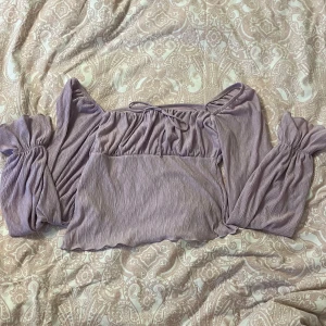 Lila topp från Gina Tricot - Säljer en lila topp från Gina Tricot. Toppen har långa ärmar och en fin rynkad textur. Perfekt för en stilren look med en touch av elegans. 💜