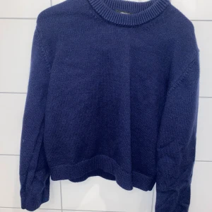Mörkblå stickad tröja från Gina Tricot - Säljer en snygg mörkblå stickad tröja från Gina Tricot. Tröjan har en klassisk rund halsringning och långa ärmar. Perfekt för kyligare dagar och enkel att matcha med olika outfits.