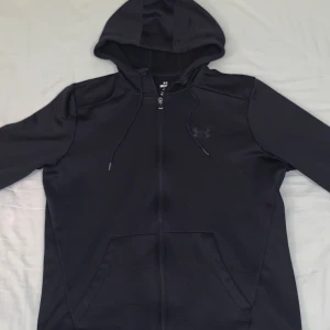 Svarta träningsbyxor från Under Armour - Snygga svarta träningsbyxor från Under Armour. De har en elastisk midja och är gjorda i ett lätt och bekvämt material. Perfekta för träning eller en avslappnad dag. Byxorna har en diskret logga på sidan.