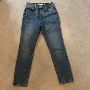 Blå jeans från Gina Tricot  - Snygga blå jeans från Gina Tricot  med klassisk femficksdesign och knappgylf. De har en rak passform och är perfekta för en avslappnad stil. Jeansen har en lätt tvättad look som ger dem en cool vintagekänsla.