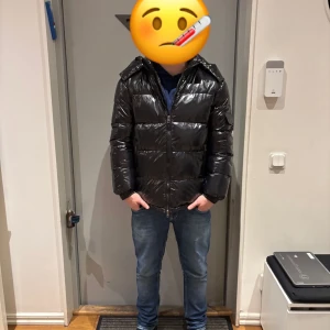 Moncler jacka - Säljer en svart Moncler jacka med glansigt material och huva. Jackan har en dragkedja framtill och är långärmad. Perfekt för kyligare dagar. Pris kan sänkas vid snabb affär