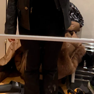 Svart skinnjacka - Snygg svart skinnjacka med dragkedja och knappar. Perfekt för en cool look. Jackan har en klassisk design med normal passning och långa ärmar.