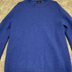 Stickad Massimo Dutti tröja - Snygg blå stickad tröja från Massimo Dutti. Perfekt för kyligare dagar med sin mjuka och bekväma passform. Tröjan har en klassisk rund hals och långa ärmar.