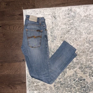 Blå jeans från nudie  - Säljer ett par tvär feta nudie jeans i en ljusblå färg jeansen är i ett bra skick men en defekt vilket är att de finns ett litet hål på ena sidan se bild 4 men det är inget som märks när de används hör av er vid frågor 