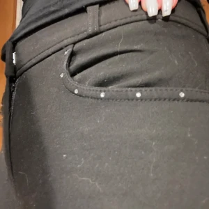 Svarta ridbyxor med glitter detaljer - Snygga svarta ridbyxor med medelhög midja och bara använd ett fåtal gånger då jag tog en paus ifrån ridningen men nu börjat igen. Byxorna har dragkedja och glitter detaljer vid fickorna. Säljer de pågrund utav att de är lite trånga runt rumpan osv och därför vill att de ska få en ny ägare. Jag har skrivit att de är storlek 40 men de känns som S/M🥰om du har några frågor så är det bara att skriva