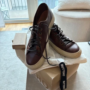 Buttero Tanino Sneakers  - Mörkbruna Buttero sneakers i storlek 42, passar mig som vanligtvis har 44,1/2 -45 i skor då dem är väldigt stora i storleken. Inte använts på väldigt länge eller mycket. Inköpta på Jupiter i Stockholm nypris 4 199:-. Skickas med extra vita skosnören från Buttero, samt i orginalkartong och med tillhörande skopåse. 