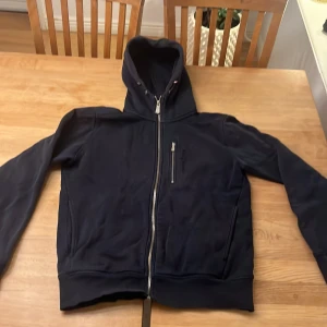 Svart hoodie med dragkedja - Säljer en mörkblå sailracing hoddie. Hyfsat bra skick med den enda problemet är ärmanrna. Kan diskutera priset. Storlek S 