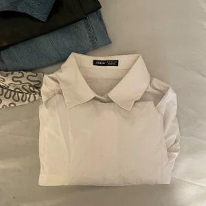 Vit skjorta från Shein - Säljer en stilren vit skjorta från Shein. Skjortan har en klassisk krage och är långärmad, perfekt för en snygg och enkel look. Passar bra till både jeans och kostymbyxor.anväd få gånger. Enkle och fin kjorta