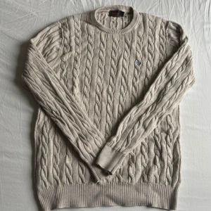 Kabelstickad tröja från Morris - Säljer en creméfärgad morris tröja i 100% Pima cotton. Storleken är L men sitter som M. Mycket bra skick förutom en liten fläck som knappast syns(bild 3). Skriv vid funderingar. 