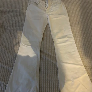 Vita midweast  jeansbyxor  - Snygga vita jeansbyxor med bootcut-stil. De har en klassisk femficksdesign och är högmidjade för en bekväm passform. Perfekta för en stilren look.