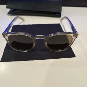 Transparenta solglasögon från Saint Laurent - Tja ett par helt nya solglasögon från Saint Laurent (ÄKTA). Ramen är stilren och modern, perfekt för en trendig look. Kommer med ett elegant fodral med Saint Laurent-logga. Ny pris runt 3000, mitt 950