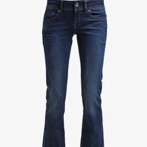 Mörkblå jeans från G-Star RAW - Snygga mörkblå jeans från G-Star RAW med klassisk femficksdesign och knappgylf. Jeansen har en bootcut-stil och är tillverkade i slitstarkt denim. Perfekta för en avslappnad look.