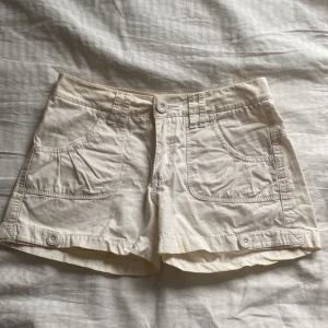 Vita shorts med knappar - Snygga vita shorts med knappar framtill och stora fickor. Står storlek 158 men skulle säga att den passar någon med XS! Sitter lowrise🤩 