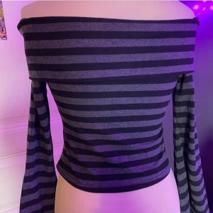 Randig offshoulder topp - Säljer en superfin randig offshoulder topp i svart och grått. Den har långa ärmar och en croppad passform som är perfekt för både vardag och fest. Toppen är i bra skick och ger en cool och avslappnad look. Perfekt för höst och vår!