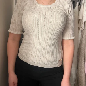 Vit ribbad topp - Säljer en stilren vit ribbad topp med korta ärmar. Toppen har en elegant passform och är perfekt för både vardag och speciella tillfällen. Den är tillverkad i ett mjukt och bekvämt material.