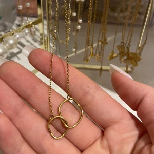 Guldhalsband med hängen - Elegant guldhalsband med två sammanlänkade ovala hängen. Kedjan är tunn och smidig, vilket ger ett stilrent intryck. Perfekt för att lägga till en touch av elegans till din outfit.